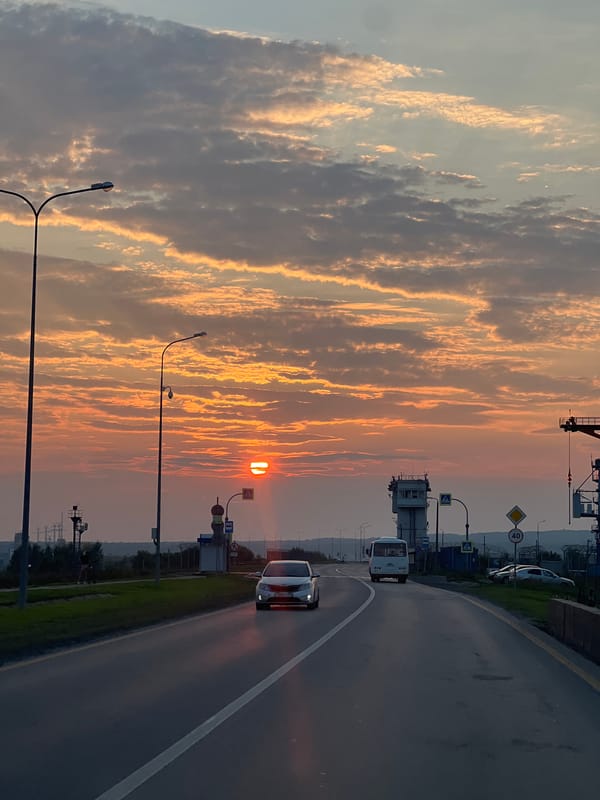 Sunset paints the sky orange over a Chaikovsky road