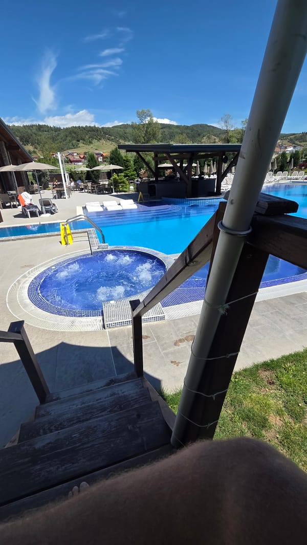 Visitor documents pool complex from elevated wooden deck in Bania