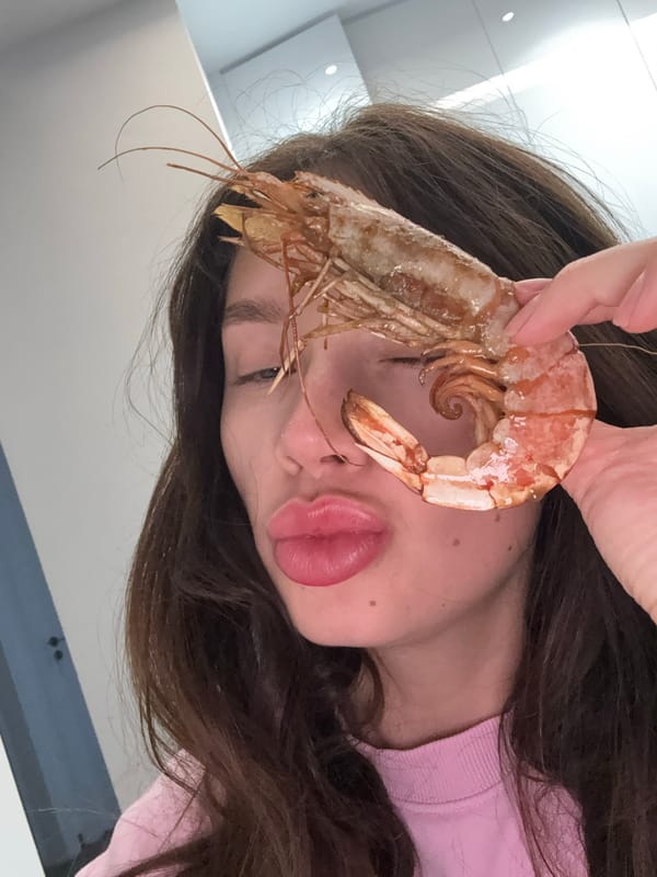 Woman poses playfully with large shrimp in Cyprus