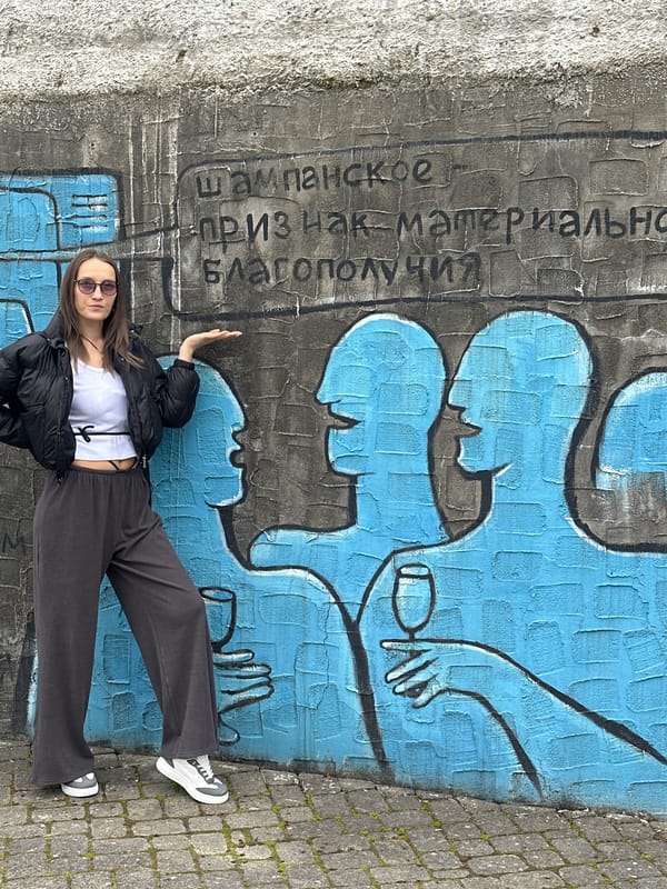 Woman in black jacket photographed at cherry blossoms, graffiti