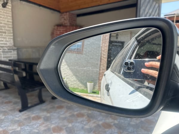 Side-view mirror reflects phone in hand, Masazir streetside