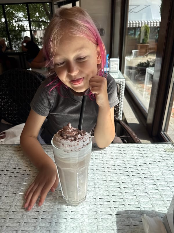 Child with pink-streaked hair enjoys meal at outdoor cafe