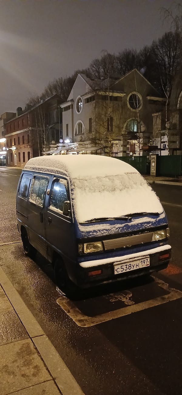 Snow-covered minivan displays children's drawings in Moscow street