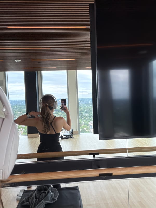Woman takes selfie by window in Austin workout gear