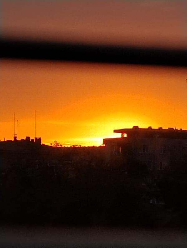 Urban sunset creates orange-yellow sky backdrop for silhouetted towers