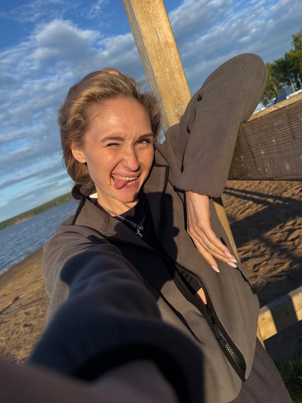Woman takes playful selfie at Chaykovsky waterfront during golden hour