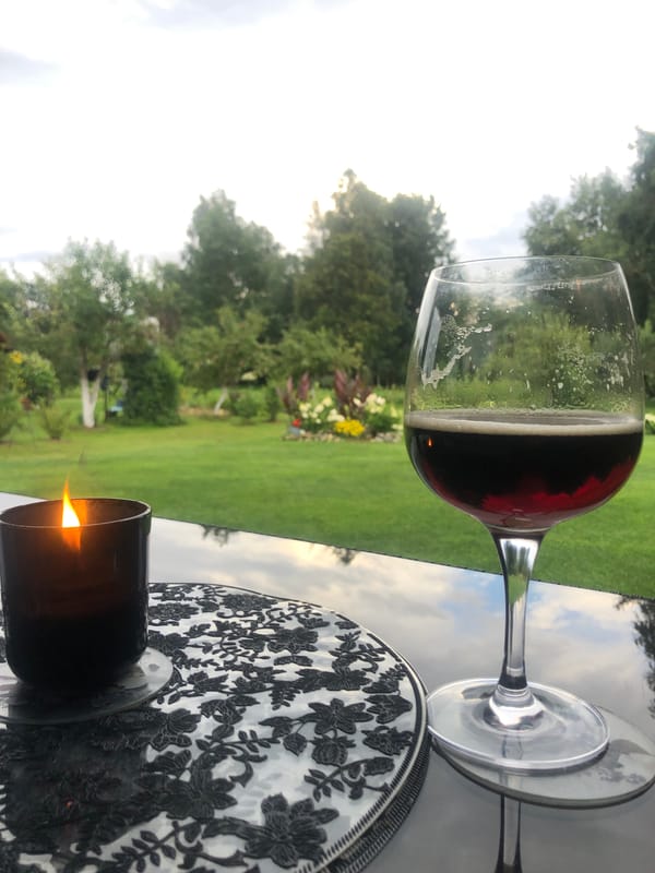 Candle and drink on a reflective surface in an overcast garden