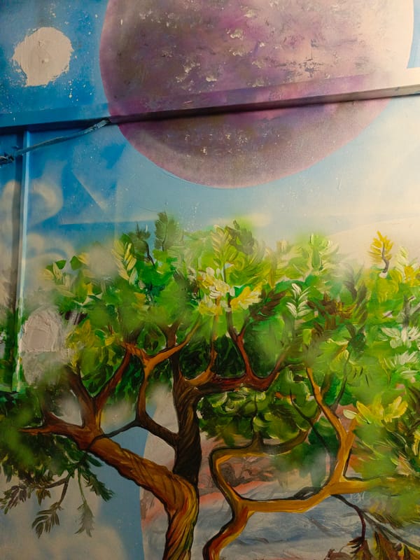 Tree mural with green foliage documented on building wall