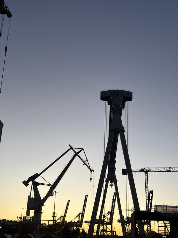 Gdynia shipyard cranes cut silhouettes against a twilight sky