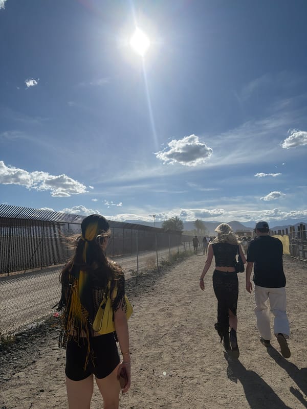 People gather near fence and tent structure in Indio