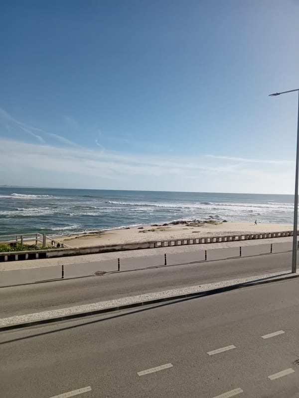 Coastal scene captured with rough seas, parked cars, pedestrians