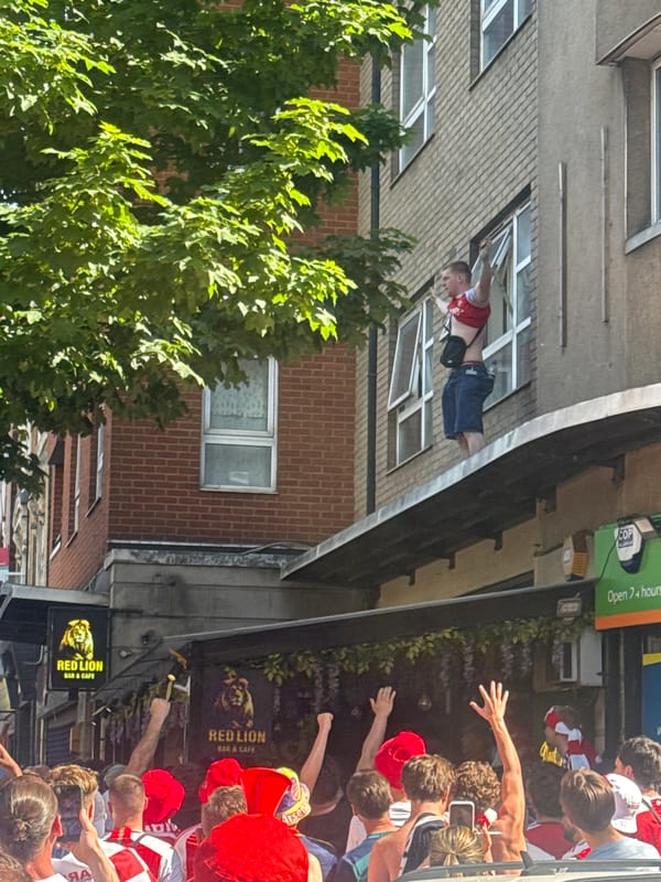 Arsenal fans celebrate outside London pub, supporters climb rooftops