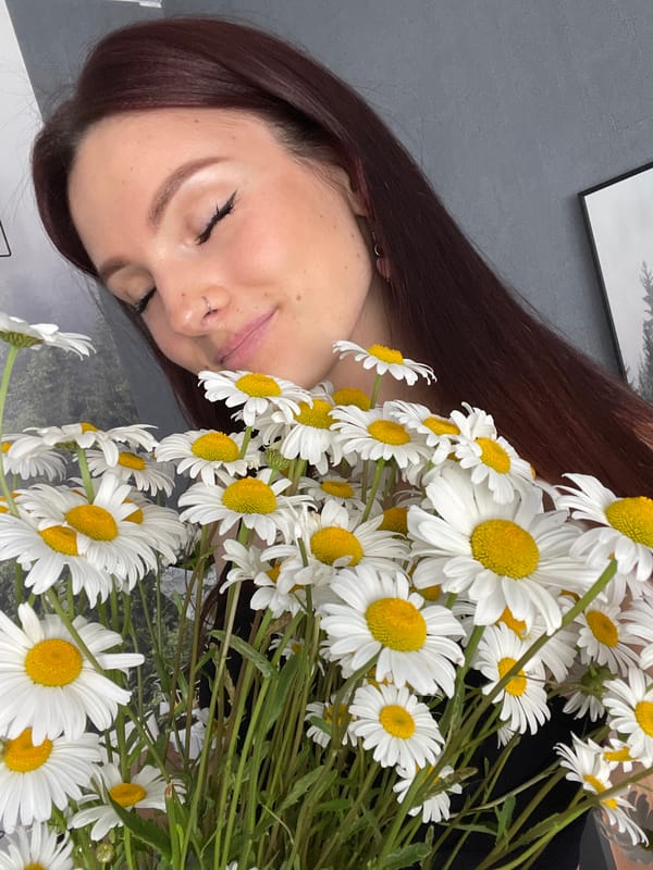 Holding white daisies, eyes closed, a calm and quiet moment.