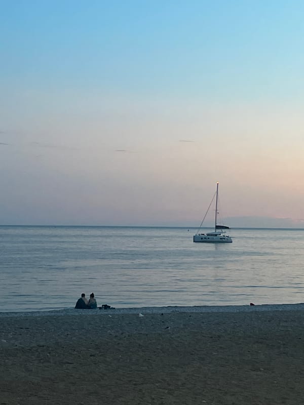 Twilight captured along Budva's Adriatic coastline with sailboats and city lights