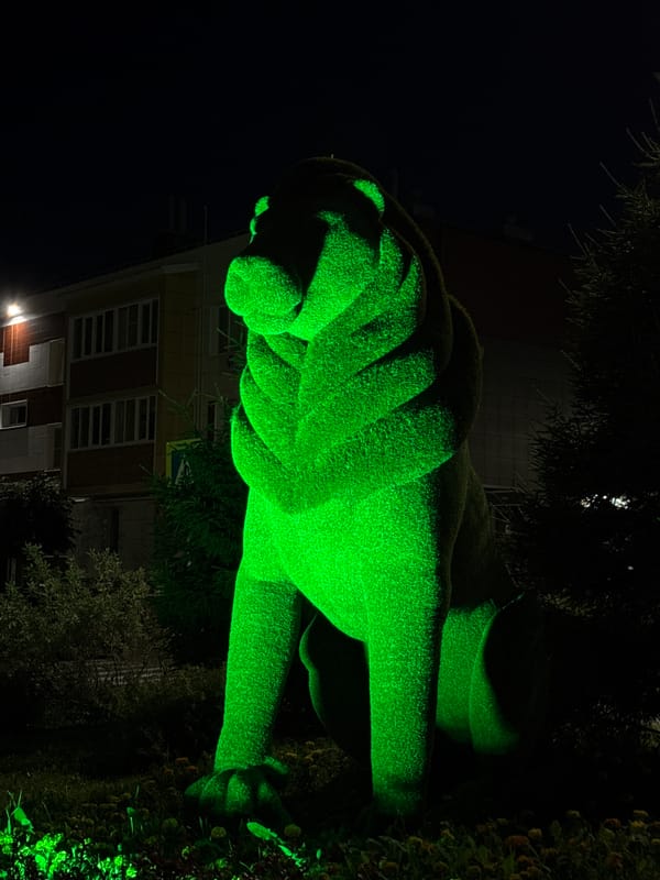 Green-lit topiary animals glow in a Russian park at night