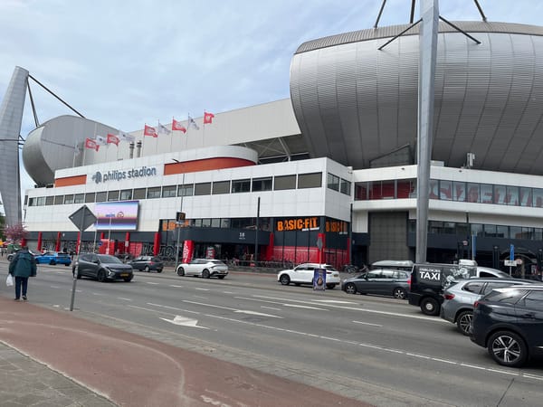 Pedestrian walks near Philips Stadion amid regular street traffic