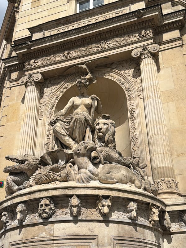 Stone sculpture photographed on Parisian building facade in bright sunlight