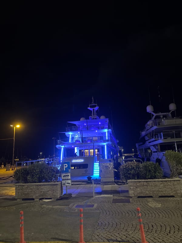 Blue-lit yacht docked at Rijeka waterfront at night