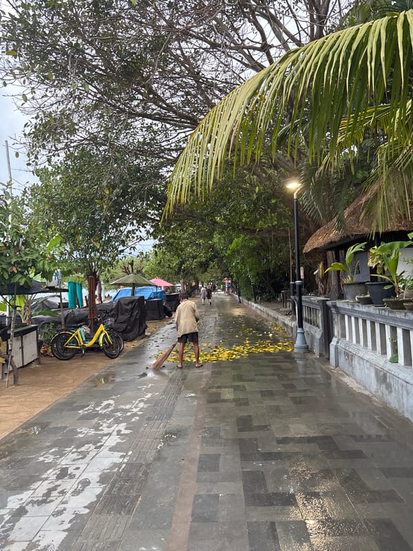 Morning beach life documented across Denpasar waterfront under cloudy skies