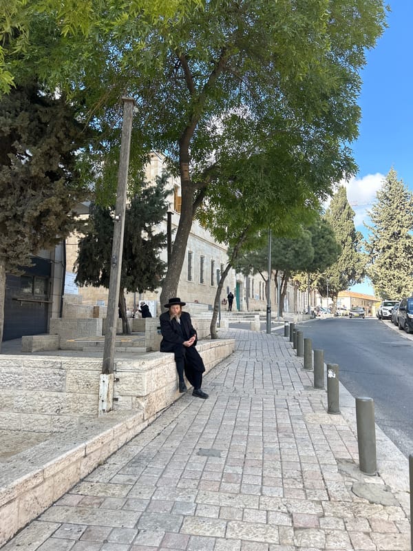 Two people rest on stone ledges in Jerusalem