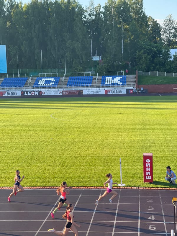 Track and field meet underway at a blue-seated outdoor stadium