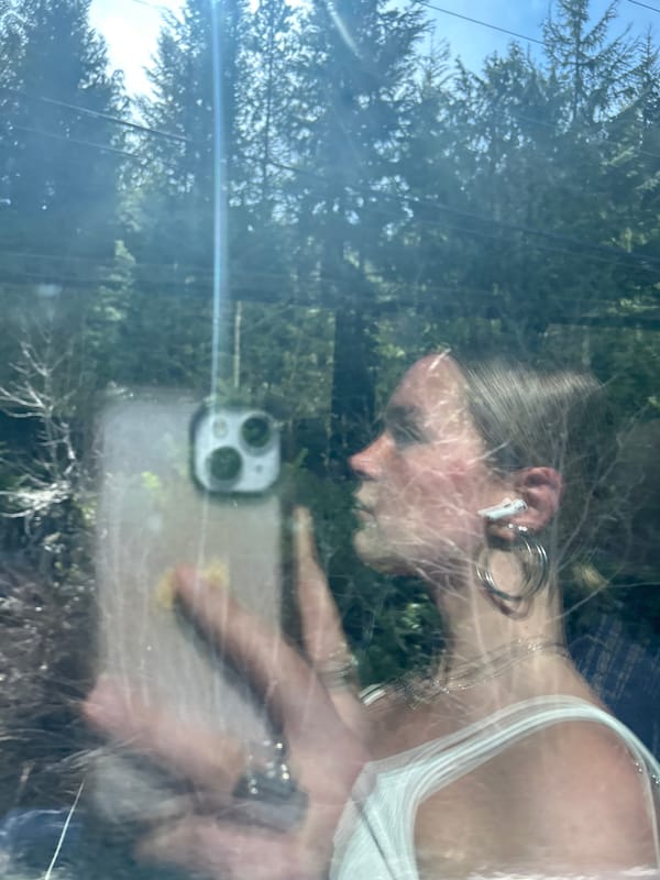 Person with smartphone captured in car window reflection, Whistler