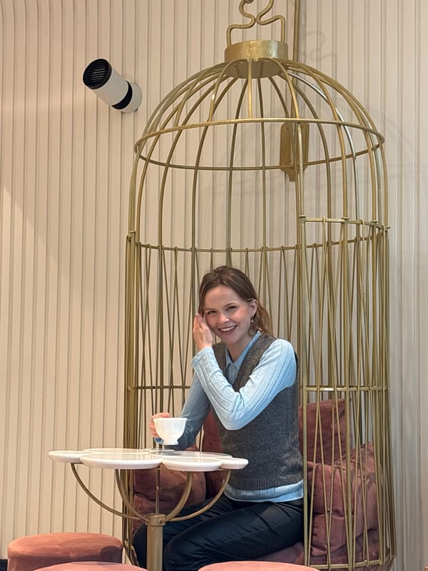 Woman sits in golden birdcage with pillows, Saint Petersburg