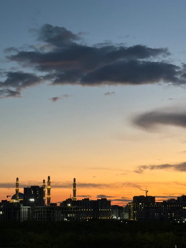 Astana skyline at dusk, minarets lit against the fading sky