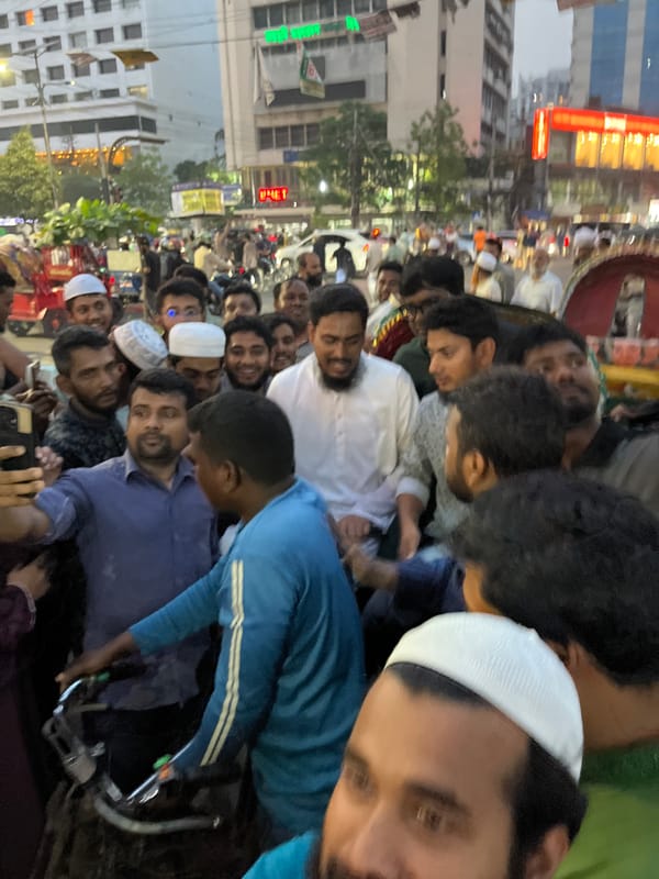 Large crowd in traditional dress gathers on Dhaka street