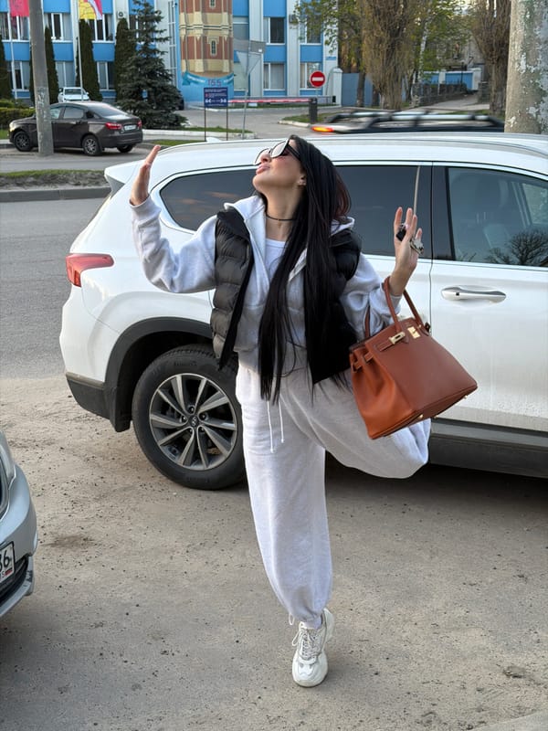 Person leans against white SUV in Voronezh street scene