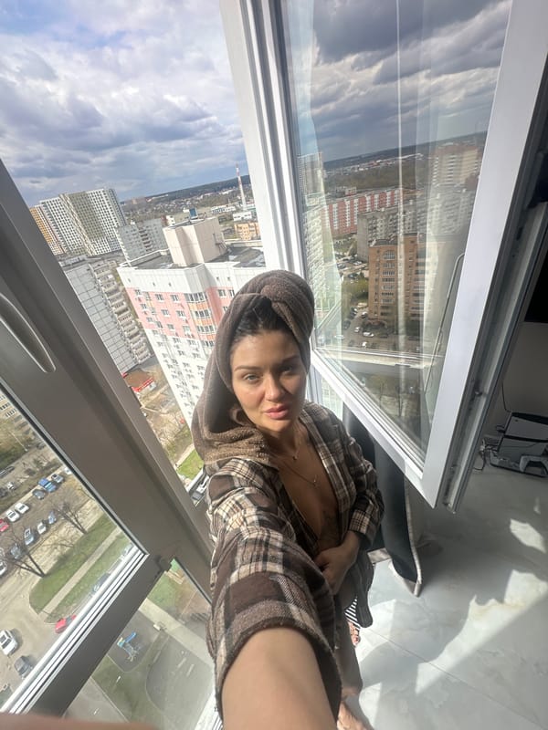 Woman in towel and robe observed near window in Moscow