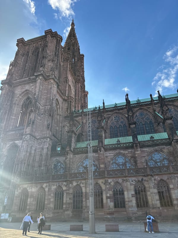 Tourist photographs Strasbourg Cathedral's Gothic architecture under blue skies