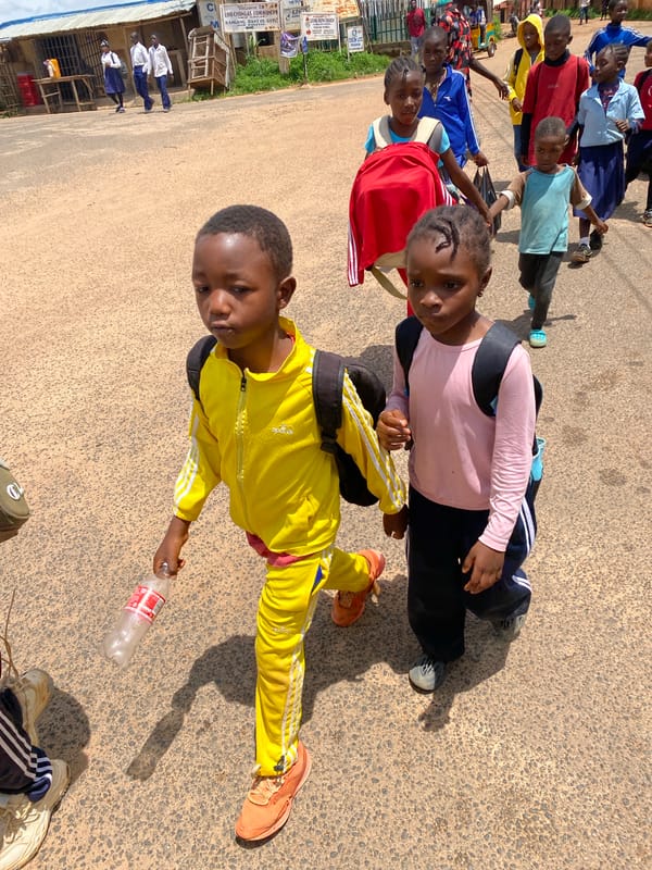 Roadside life near Jos: kids walking, red car loaded up