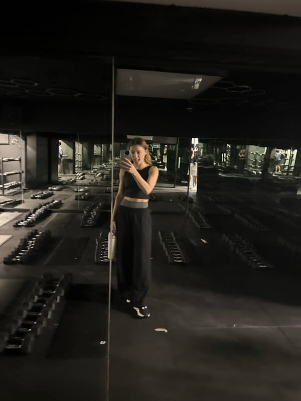 Woman takes gym selfie in mirrored workout space
