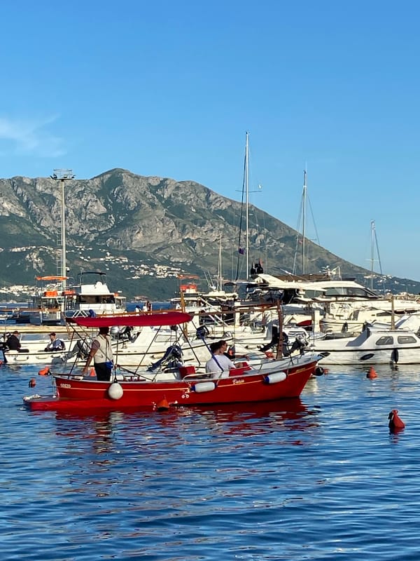 Budva waterfront activity captured with yachts, passenger boat, local cat