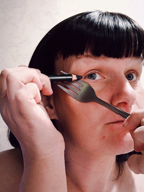 Person holds eyeliner pencil between fork tines near face