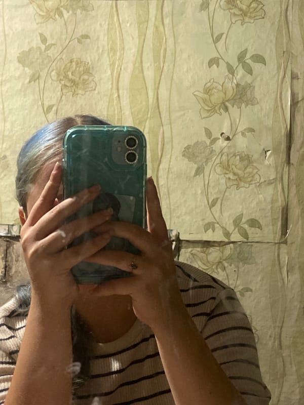 Mirror selfies in a Nova Praha room with blue-streaked hair