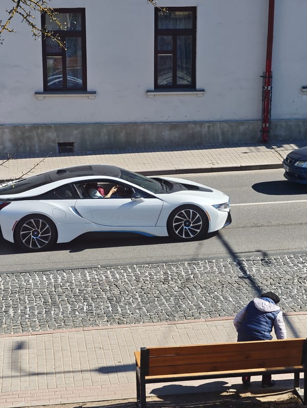 Construction worker renovates building as luxury car passes in Hrodna