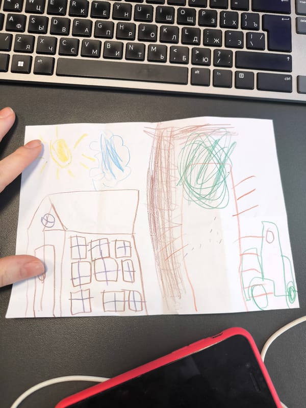 Child's Drawing Displayed on Surface Near Laptop, Hand Points