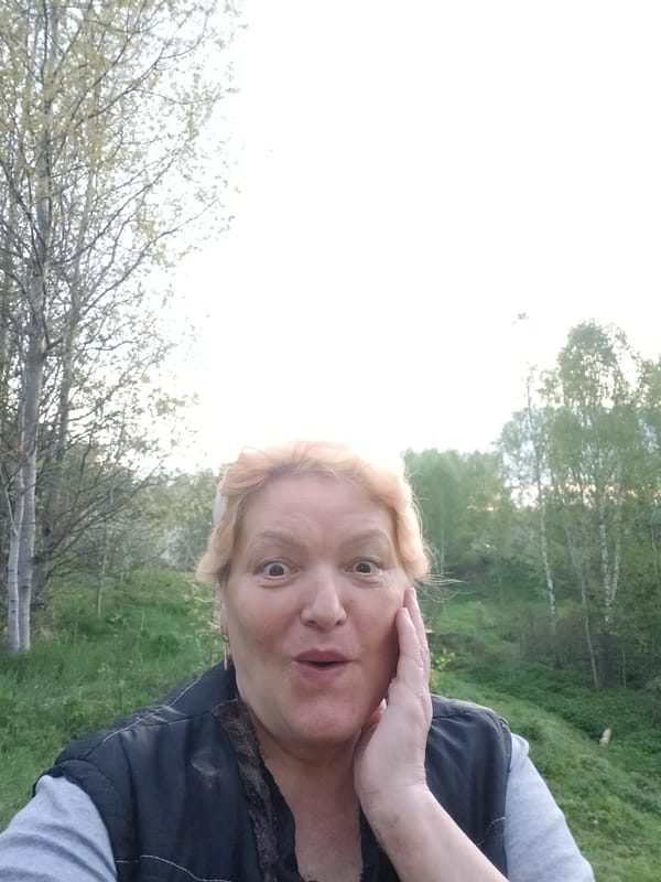 Woman documents rural landscape during evening walk in Russian village
