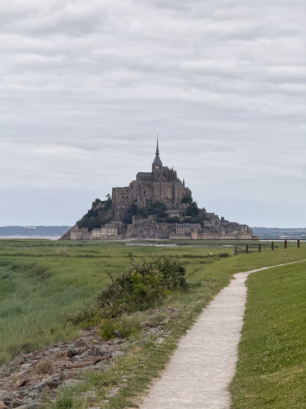 Visitor documents Mont Saint-Michel abbey under overcast skies