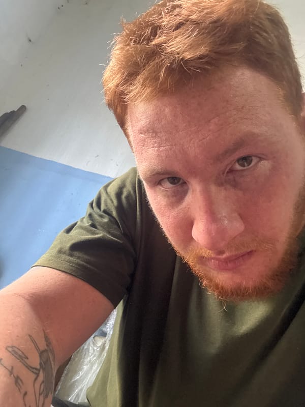 Quick selfie session, green tee, tattoos, one Russian-text shirt