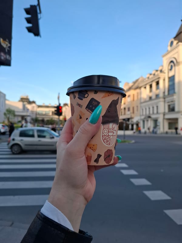 Person with teal hair holds decorated coffee cup