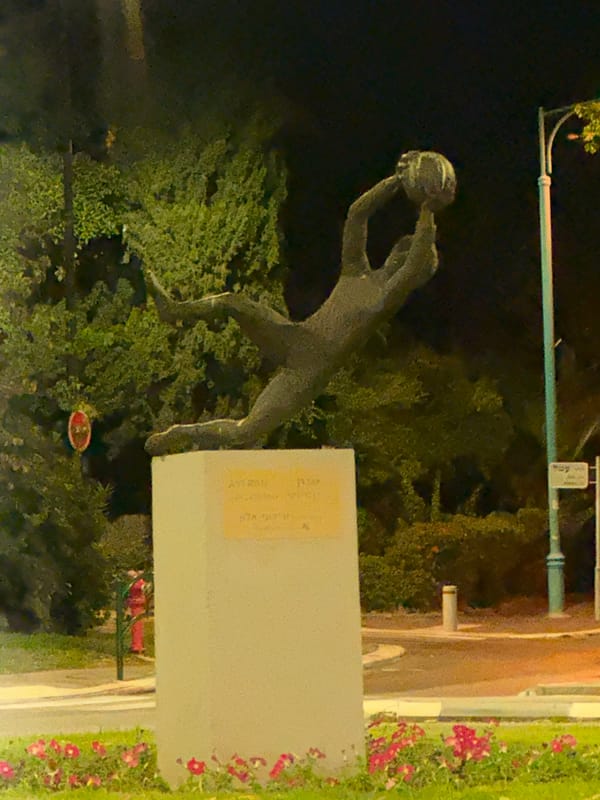 Nighttime Haifa: a roadside statue and a drive through the city