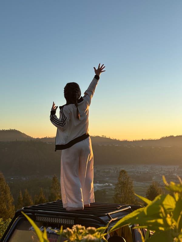 Arms raised at sunrise above Kintamani's volcanic highland views
