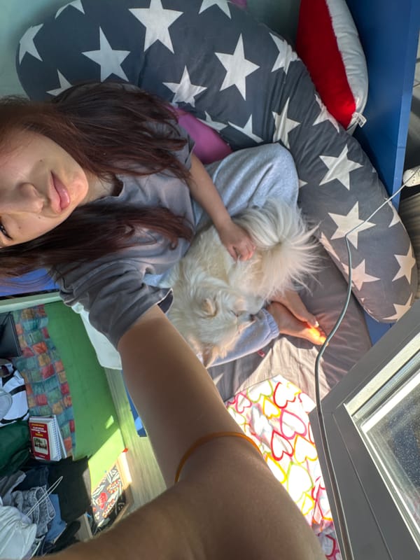 Woman and white dog rest together on heart-patterned bedding