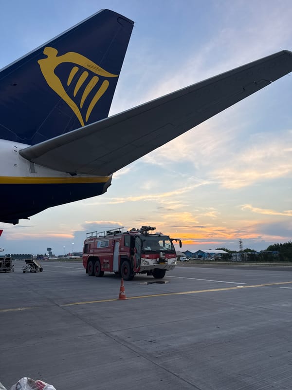 Ryanair aircraft on tarmac at sunset with ground crew activity