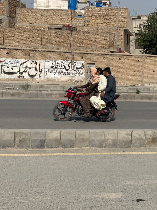 Three men ride red motorcycle in Quetta City