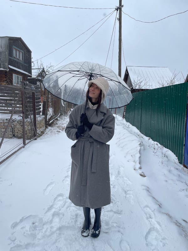Person with umbrella walks through snow in Oktyabrsky, Russia