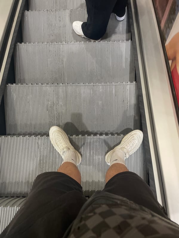 Two people ride escalator in Sofia wearing casual footwear